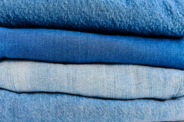 Close Pilha Jeans Azul Jeans Dobrado Mão Sobre Fundo Parede — Fotografia de Stock