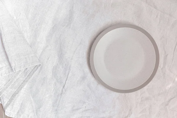 Empty circle plate on table with linen napkin. Overhead view. Space for text or menu . Business food brand template.