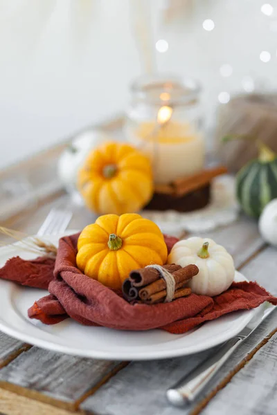 Autumn table setting with pumpkins and candles. Zero waste concept, natural elemets. Fall home decoration for festive Thanksgiving family dinner. Wooden table.