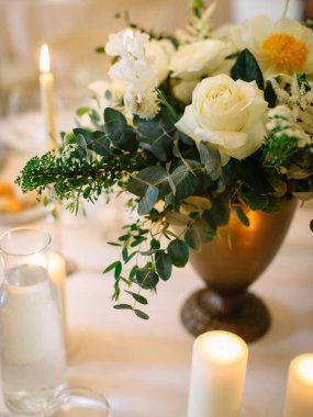 Served beautiful table, three glasses, plates with eucalyptus, breakfast bread, candles, and a bouquet