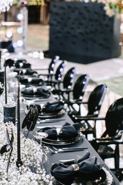Serving and decorating a banquet table in black with white flowers and black candles at an outdoor party.
