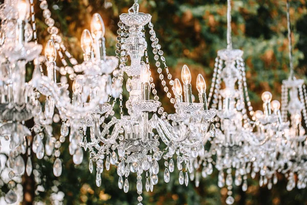 Crystal chandeliers glow in the evening in the park as a decoration.
