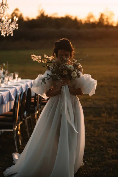 Bride Airy White Dress Bouquet Flowers Stands Backlight Setting Sun — Zdjęcie stockowe