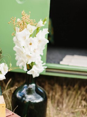 White gladioli stand in a black vase in nature.
