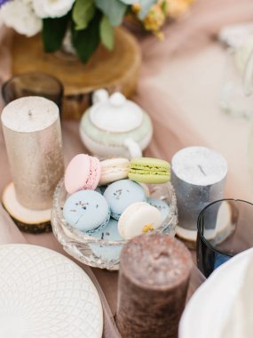 Blue, pink, green, and white macaron cakes stand on a table with sparkling candles.