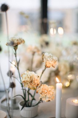 Ziyafet masasının düğün dekoru. Ön planda yanan mumlar, vazolarda beyaz karanfiller.. 