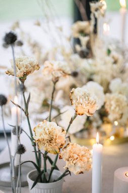 Ziyafet masasının düğün dekoru. Ön planda yanan mumlar, vazolarda beyaz karanfiller.. 