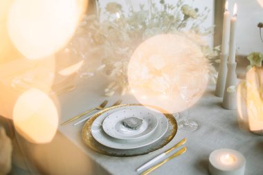 Düğün ziyafeti masasının süsü. Altın ve beyaz tabaklarda dekoratif bir taş var. Ön planda 