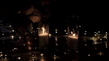Karanlıkta cam vazolarda beyaz mumlar yakmak. Güzel cam vazo, düğün süsü ve yanan mum..