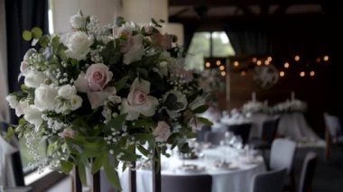 Düğün çiçeği aranjmanı masada pembe ve bej renklerde. Parti ziyafeti masasındaki güllerin çiçekli kompozisyonları. Yavaş çekim.