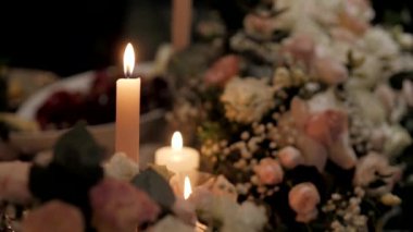 Karanlıkta cam vazolarda beyaz mumlar yakmak. Düğün dekorlu ve yanan mumlu güzel cam vazo. Yavaş çekim.