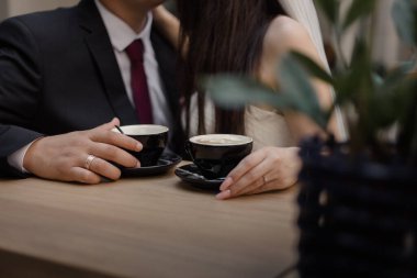 Gelin ve damat kahve içerler. Düğün günü gelin ve damat için bir fincan kahve. Birbirine aşık genç bir çift bir kafede oturuyor, sarılıyorlar, elleriyle birbirlerine dokunuyorlar..