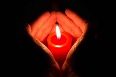 Yanan bir mum tutan eller