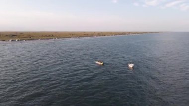 Bir sürat teknesinin şişme bir muz teknesini yüksek hızda çekerken görüntüsü. Video, tekneyi takip eden bir İHA tarafından çekildi. Deniz kenarında gezinti, deniz eğlencesi. 