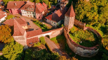 Romanya 'daki Sighisoara ortaçağ kasabasında kuleleri olan güçlendirilmiş bir kapının hava fotoğrafçılığı. Kasvetli duvarları ve kuleleri olan kasvetli bir şehrin üzerinde hava fotoğrafçılığı.