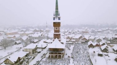 Aerial video of the wooden church at Sapanta cemetery in Maramures county, Romania in winter season. Footage was done from a drone while flying backwards from the church to reveal the cemetery.