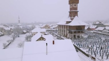 Aerial video of the wooden church at Sapanta cemetery in Maramures county, Romania in winter season. Footage was done from a drone while flying around the church and picking up altitude.