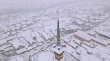 Aerial video of the wooden church at Sapanta cemetery in Maramures county, Romania in winter season. Footage was done from a drone while flying backwards from close proximity of the tower.