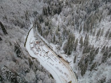 View from above of a touristic train station located in Maramures county, Romania, Shot from a high altitude in winter season. Aerial view of a narow gauge steam train station