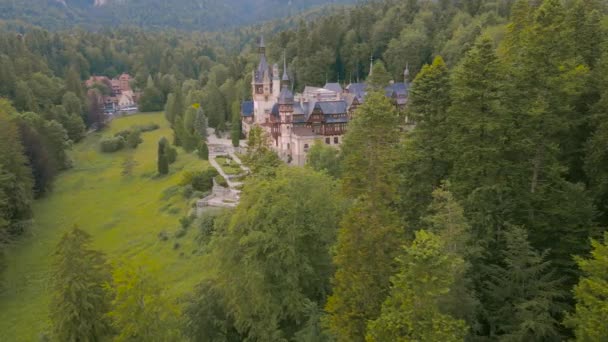 在罗马尼亚Sinaia的Peles城堡上空鸟瞰 空中录像是由一架无人驾驶飞机拍摄的 而银行则在树梢上方的低空飞行 并在树梢上发现了城堡 — 图库视频影像