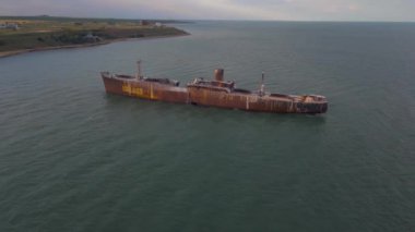 Romanya 'nın Costinesti plajının yanındaki Karadeniz' de paslı bir gemi enkazının insansız hava aracı görüntüleri. Geriye doğru uçarken bir drondan çekilen hava görüntüsü enkazı ortaya çıkarmak için sola dönüyor.