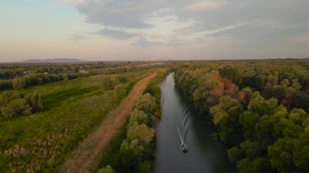 ドナウのデルタの運河の空中映像 後方に飛んでいる間にドローンから撮影された モーターボートと美しい日の出の風景 — ストック動画