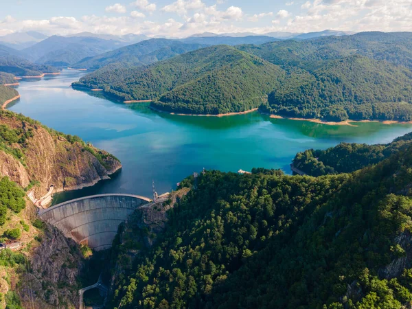 Aerial photography of Vidraru dam, in Romania. Photography was shot from a drone from above canyon at Vidraru lake with the dam and the lake in the view and mountains in the background.