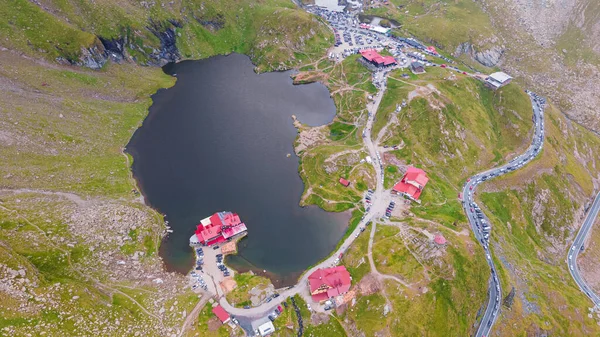 Romanya 'nın Transfagarasan yolundaki Balea Gölü' nün insansız hava aracı fotoğrafları. Fotoğraf, gölün yukarısından bir dron tarafından çekildi. Kamera gölün, kulübelerin ve kıvrımlı yolun üst görüntüsü için eğildi..