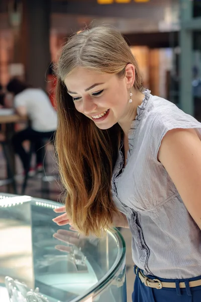 Blonde girl considers jewelry in the store — Stock Photo, Image