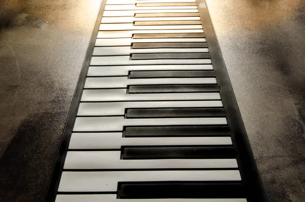 Close-up of a flat piano keyboard, top view. Piano keys on a textured concrete background. soft toning. warm soft light Jazz music sty
