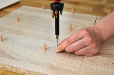 Metal bir mobilyayı vidalayan kadın eli. Tornavidayla vida. Kadın dairede kendi başına mobilya topluyor. Mobilya montajı, ev işi, DIY.