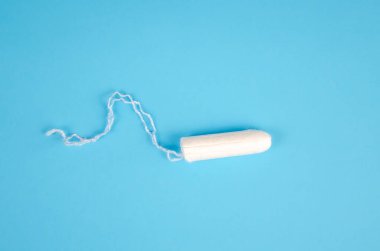 Mavi arka planda hijyenik bir kadın tamponu. Kadınlar için beyaz pamuklu bez, regl sırasında korunma. Kadın hijyeni..