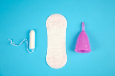 Adet bardağı, tek kullanımlık ped ve mavi arka planda tampon. Yeniden kullanılabilir regl bardağı, çevre dostu seçim. Kadın hijyen ürünleri. Sıfır atık.