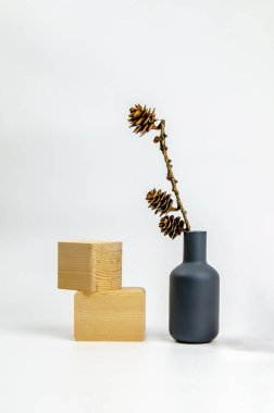 Doğal malzemelerden dekoratif iç unsurlar. Kil vazoda kuru bir tarla kuşu ve beyaz arka planda tahta küpler. Kavram: minimalizm, çevre dostluğu, sıfır atık
