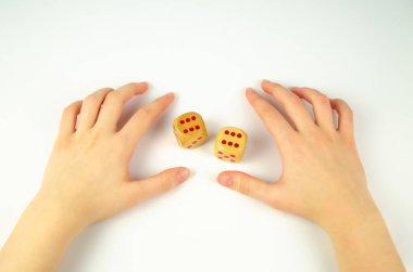 Zarif kadın eli beyaz arka planda tahta kemikler tutuyor. Kura çekme, kazanma, şans. Düşen zarlarda iki altı.