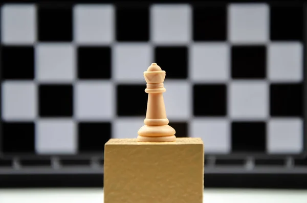 チェスの駒 女王はチェス盤のセルを背景に表彰台に立つ リーダーシップ 目標達成の概念 チェスクイーンのクローズアップ — ストック写真