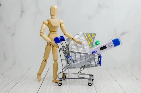 男性の木製の人形は 温度計を備えたショッピングカートを運んでいます 医療の概念は 医療用品の購入 テキストのスペース — ストック写真