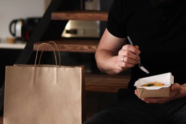 Ofis işyerinde sağlıklı bir öğle yemeği. Yemek paketinden beslenme yemeği yiyen bir adam..