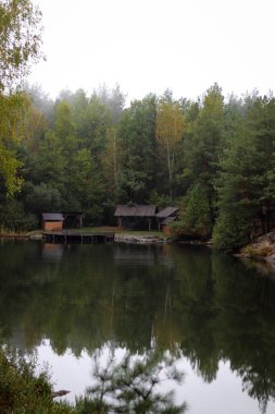 Çam ormanındaki gölün yanındaki ahşap ev. Ormanın içindeki yazlık ahşap göl evi .