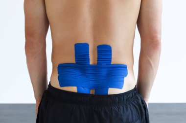 Fizyoterapist erkek hastanın beline kinesio bandı uyguluyor. Kineziyoloji, fizik tedavi, rehabilitasyon konsepti.