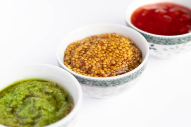 Sos seti - ketçap, pesto ve hardal tohumları sos kabında beyaz arka planda izole edilmiş.