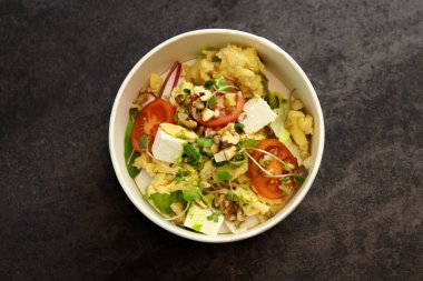 Çırpılmış, peynirli, domatesli, cevizli ve mikro yeşillikli bir kase. Ekolojik bir karton kutunun içinde. Sağlıklı yemek teslimatı kavramı.