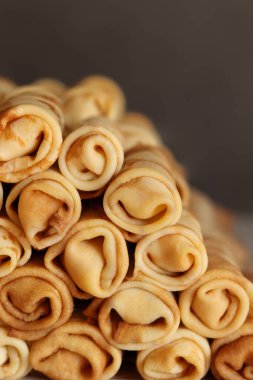 Etle bükülmüş bir yığın krep. Arka planda geleneksel Ukrayna usulü ince Rus krepleri var. Lezzetli sabah kahvaltısı ya da öğle yemeği. Maslenitsa için ev yemeği. Pankart. Görüntüyü kapat.