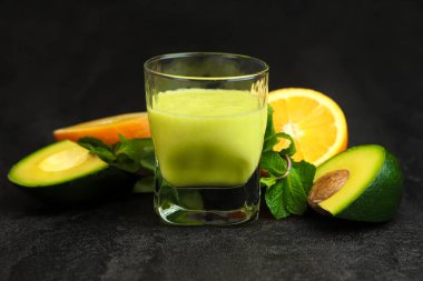 Siyah arka planda cam bardakta yeşil meyve püresi. Kereviz, elma, avokado, portakal ve nane. Superfood, detoks, diyet, sağlıklı yiyecekler..