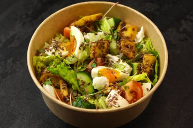 Kızarmış kalamar, yumurta, domates, salatalık, marul, krem peynir ve keten tohumu salatalı siyah arka plan. Gıda dağıtım hizmeti ve günlük istihkak kavramı.