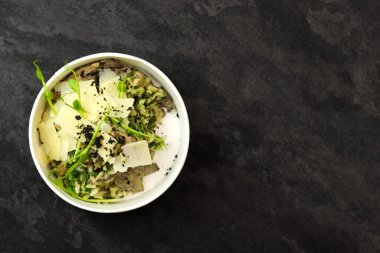 Mantarlı risotto ve siyah arka planda parmesan. Restoran yemeği teslimatı. Üst Manzara. Metin için boş alan. Sağlıklı gıda konsepti.