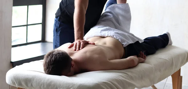 Therapist doing back sports massage to male patient athlete at studio