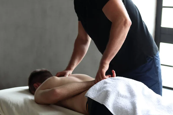 Terapist, stüdyoda hasta erkek sporcuya masaj yapıyor.