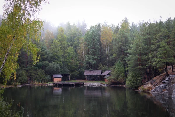 Wood house beside the lake in pine forest. Summer wooden lake house inside forest .
