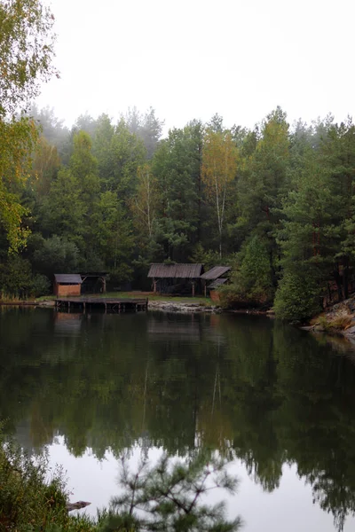 Wood house beside the lake in pine forest. Summer wooden lake house inside forest .